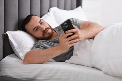 Photo of Handsome man using mobile phone in bed