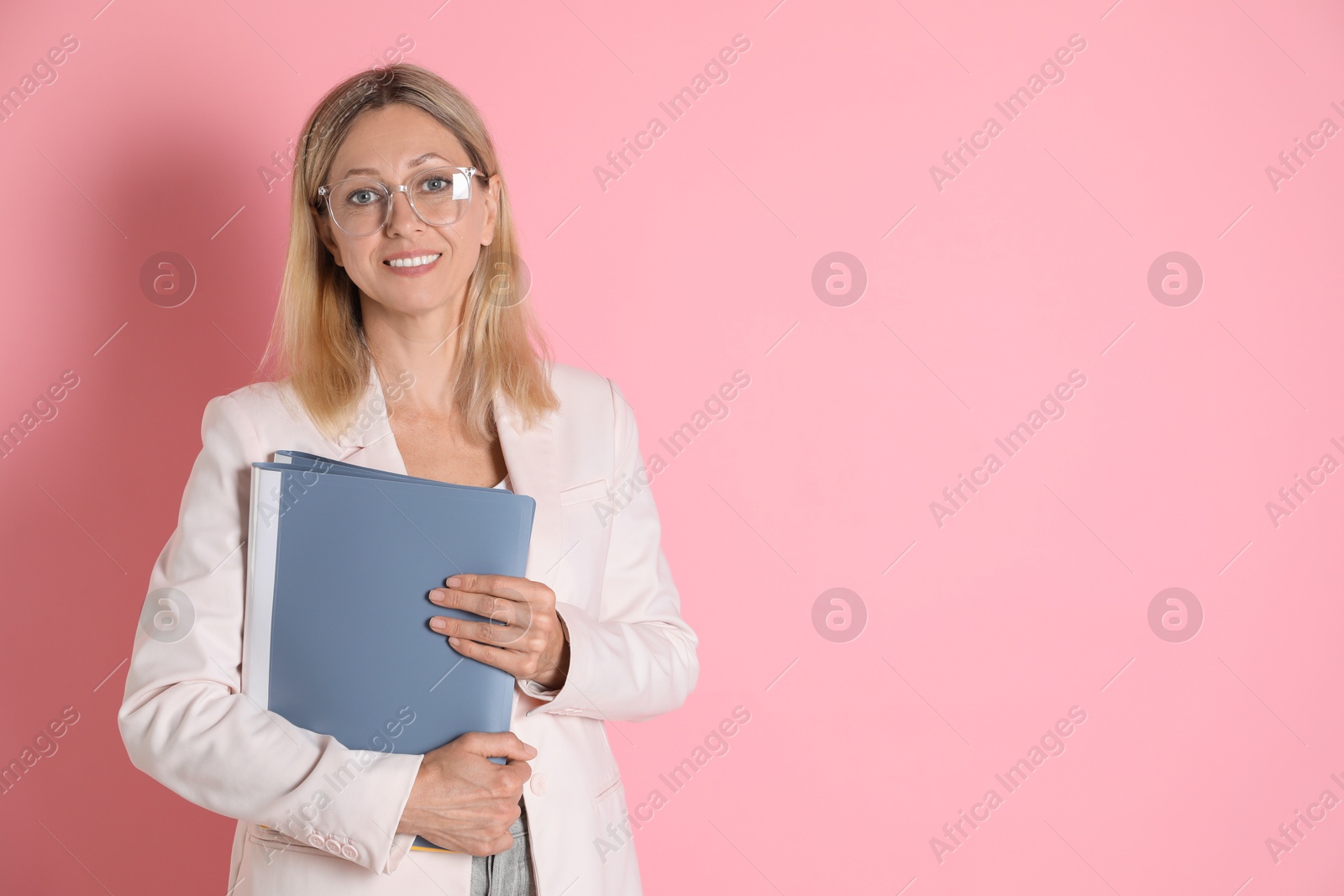 Photo of Portrait of beautiful smiling woman in glasses with folders on pink background, space for text