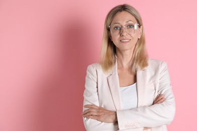 Photo of Portrait of beautiful smiling woman in glasses on pink background, space for text