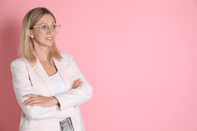 Photo of Beautiful smiling woman in glasses on pink background, space for text