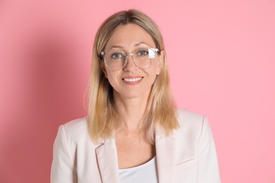 Portrait of beautiful smiling woman in glasses on pink background