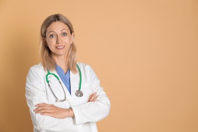 Portrait of doctor in medical uniform with stethoscope on beige background, space for text