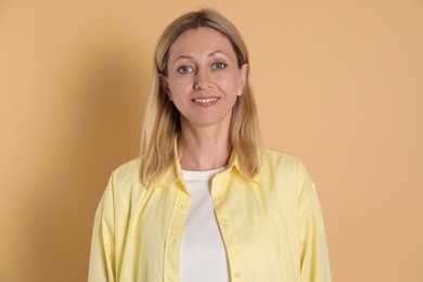 Portrait of beautiful smiling woman on beige background