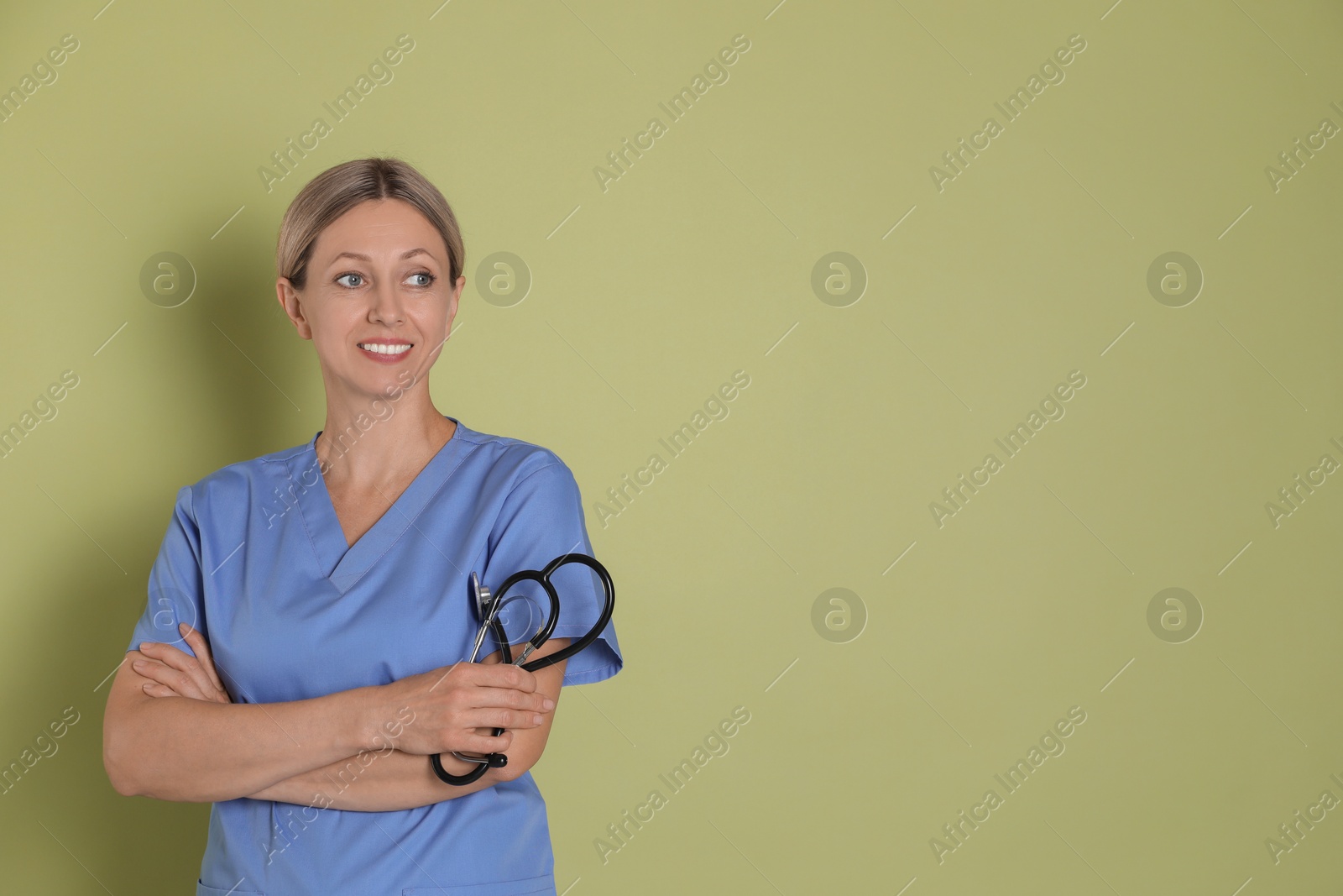 Photo of Portrait of nurse in medical uniform with stethoscope on light green background, space for text