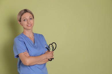 Photo of Portrait of nurse in medical uniform with stethoscope on light green background, space for text