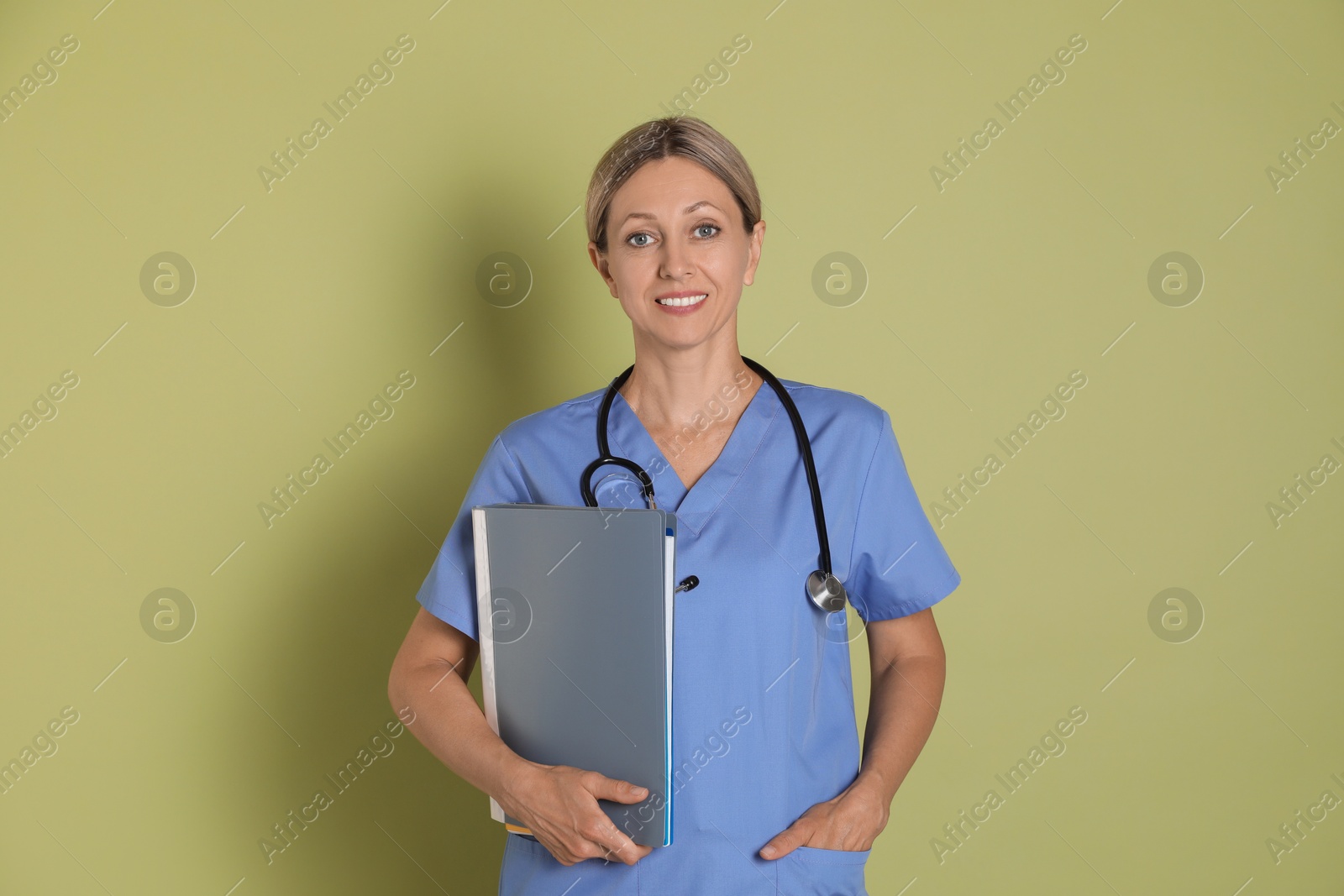 Photo of Portrait of nurse in medical uniform with folders on light green background