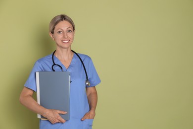 Nurse in medical uniform with folders on light green background, space for text