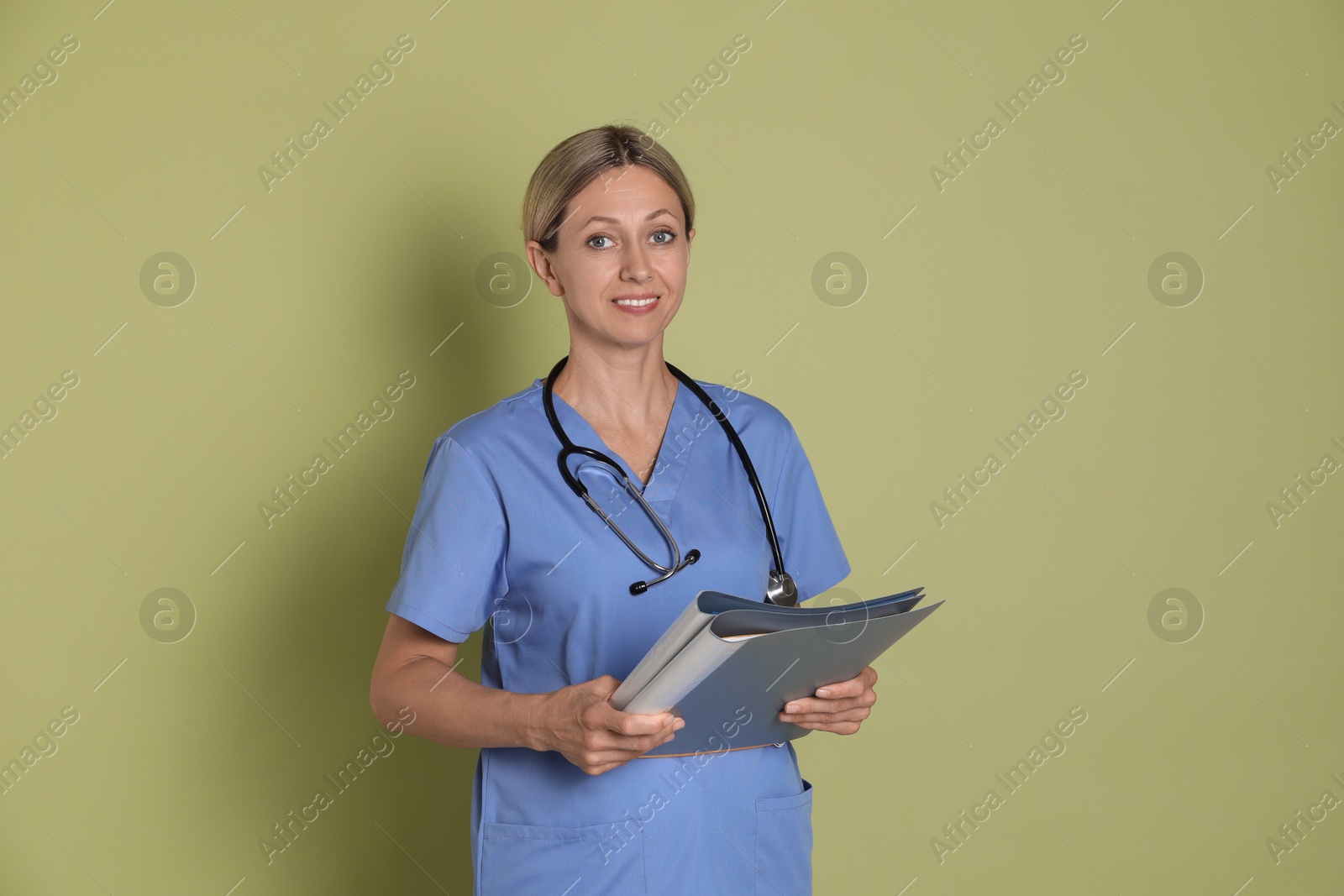 Photo of Portrait of nurse in medical uniform with folders on light green background