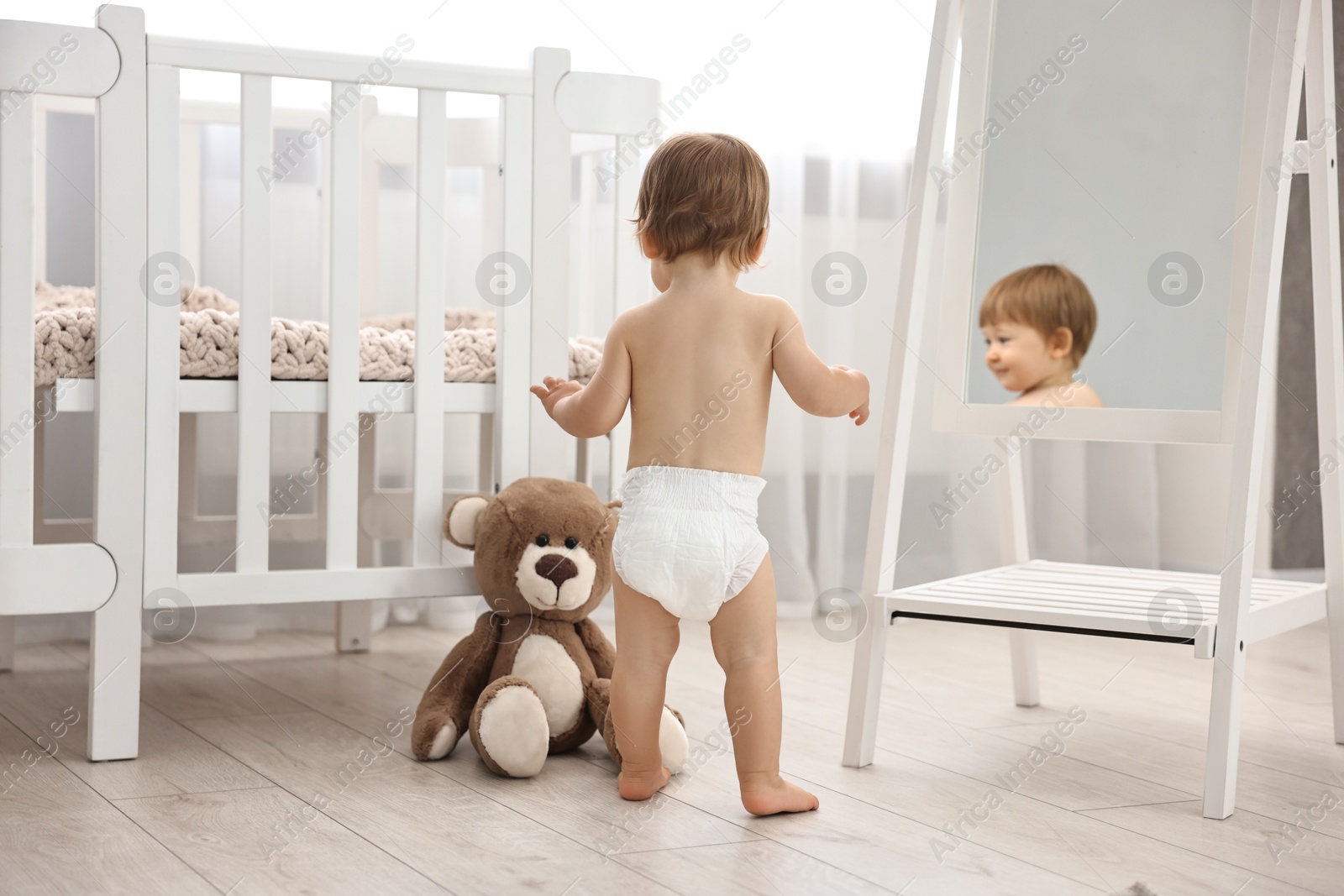 Photo of Little child in diaper with teddy bear at home