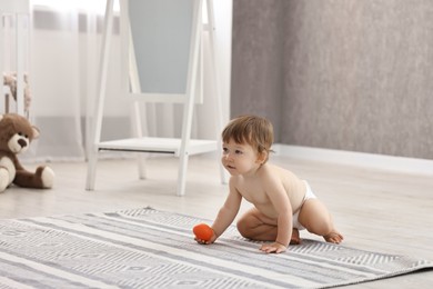 Photo of Cute little child in diaper with toy at home