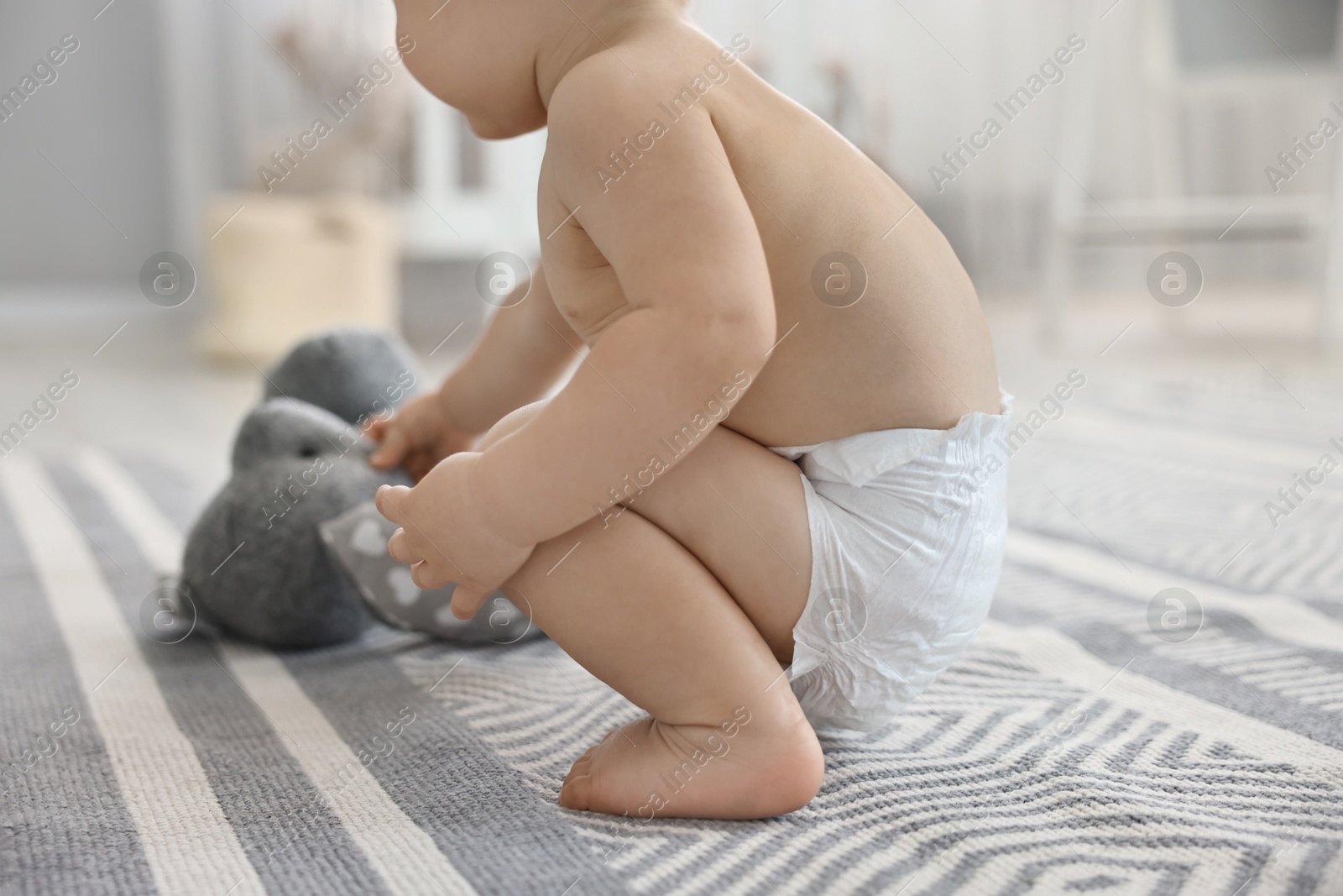 Photo of Little child in diaper with toy at home, closeup