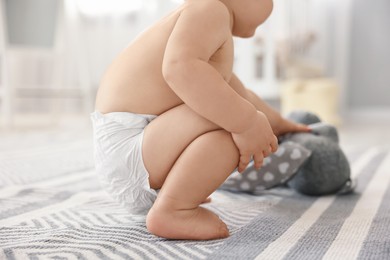 Photo of Little child in diaper with toy at home, closeup