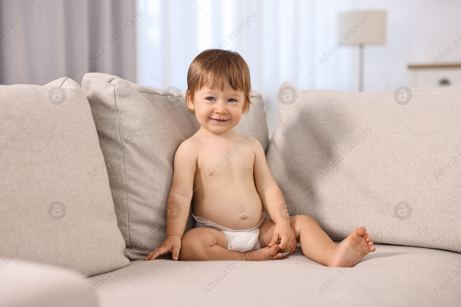 Photo of Little child in diaper on sofa at home