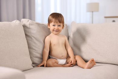 Photo of Little child in diaper on sofa at home