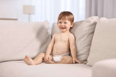 Photo of Little child in diaper on sofa at home