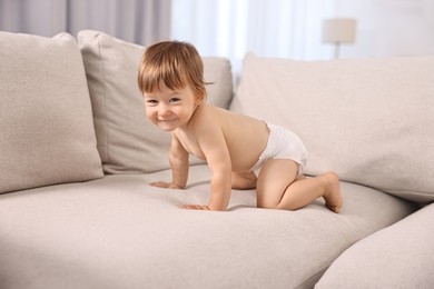 Photo of Little child in diaper on sofa at home