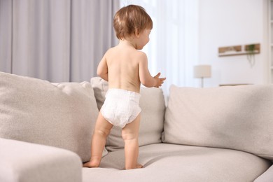 Photo of Little child in diaper on sofa at home