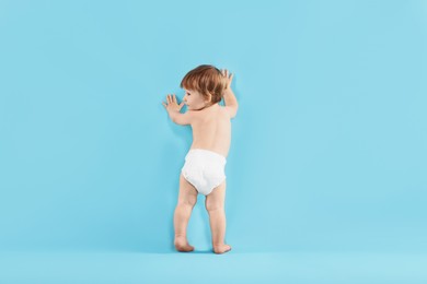 Photo of Cute little child in diaper on light blue background