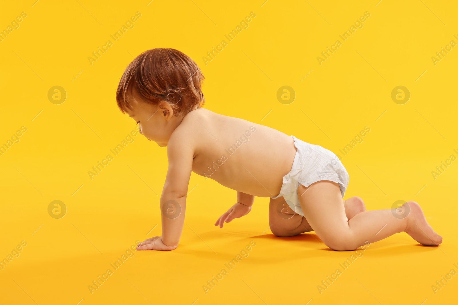 Photo of Little child in diaper with toy on orange background