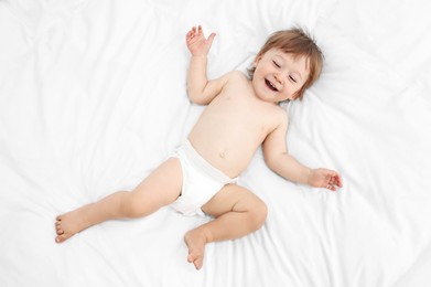 Photo of Little child in diaper on bed, top view