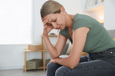 Photo of Menopause. Woman suffering from headache on sofa at home