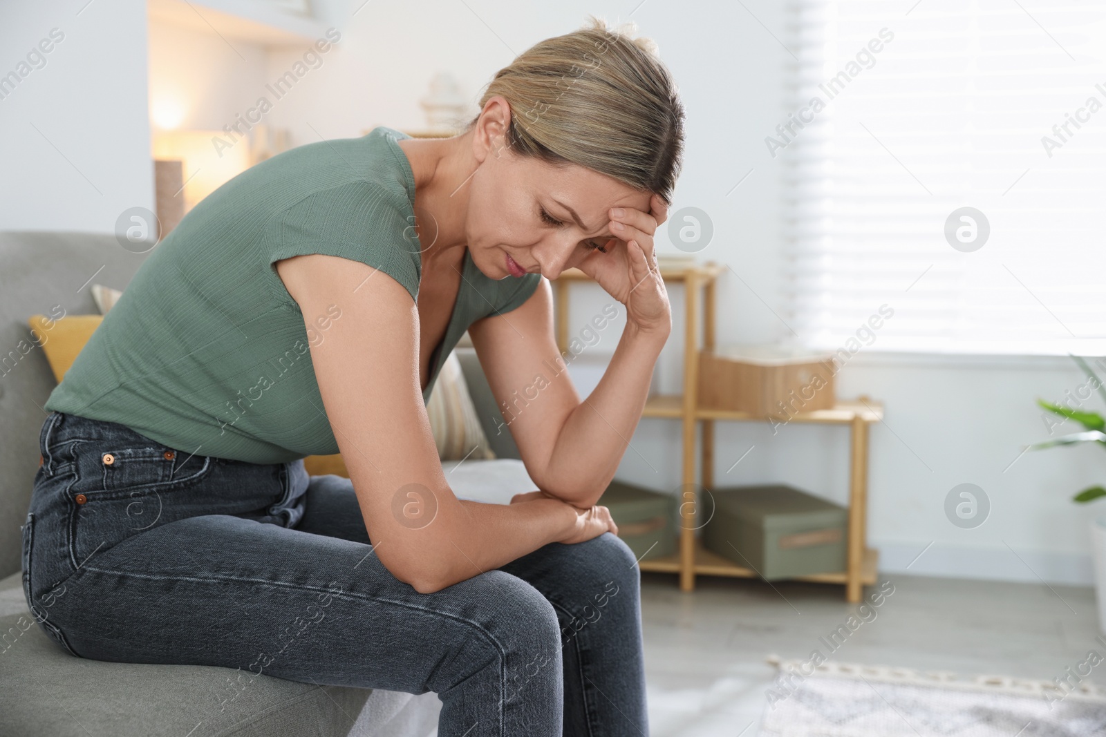 Photo of Menopause. Woman suffering from headache on sofa at home