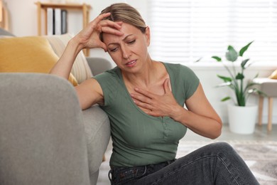 Photo of Menopause. Woman suffering from hot flash on floor indoors