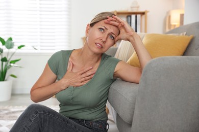 Photo of Menopause. Woman suffering from hot flash on floor indoors