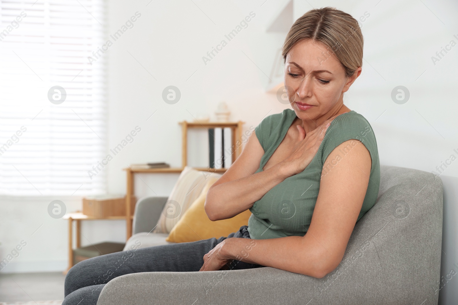 Photo of Menopause. Woman suffering from hot flash on sofa indoors