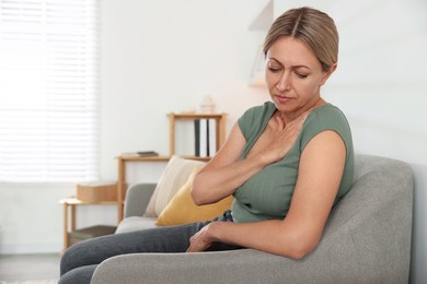 Menopause. Woman suffering from hot flash on sofa indoors