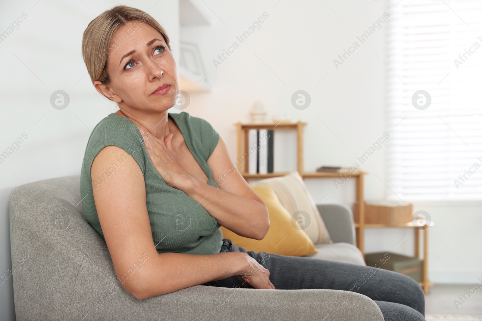 Photo of Menopause. Woman suffering from hot flash on sofa indoors