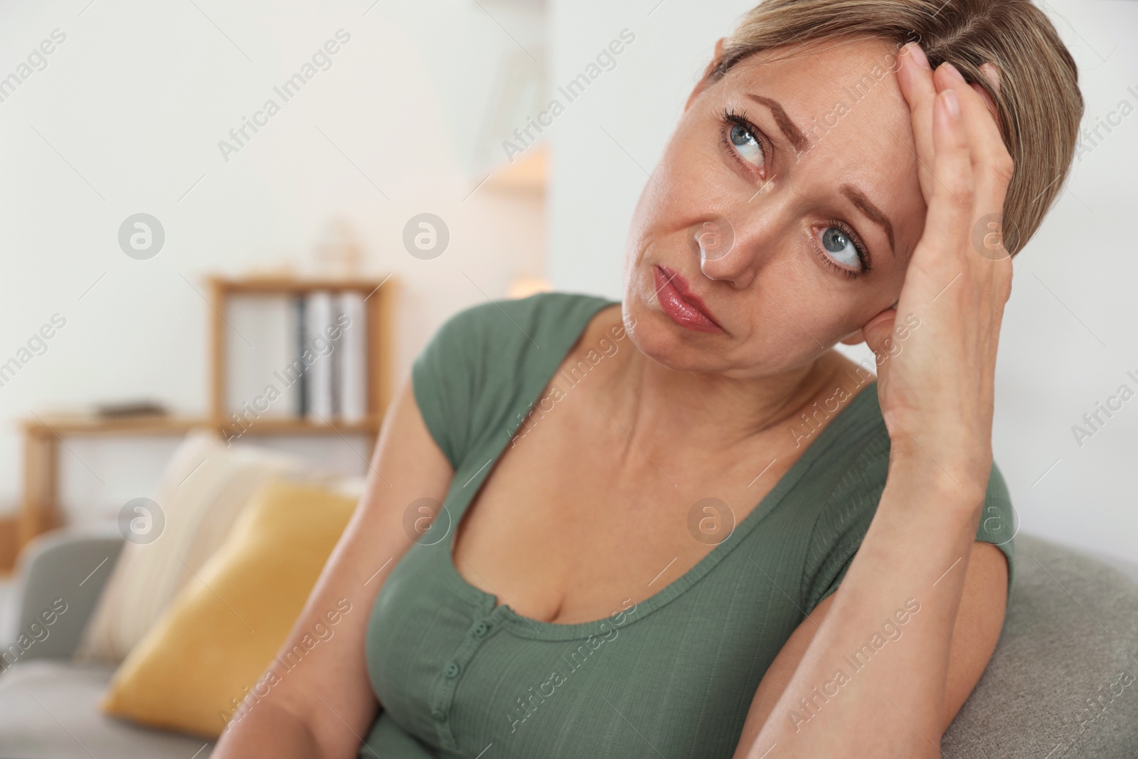 Photo of Menopause. Woman suffering from headache on sofa at home