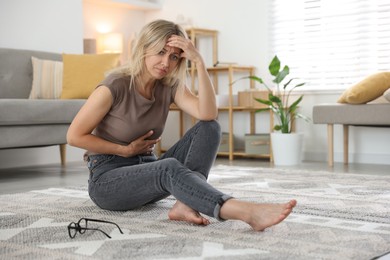 Photo of Menopause. Woman suffering from abdominal pain on floor at home