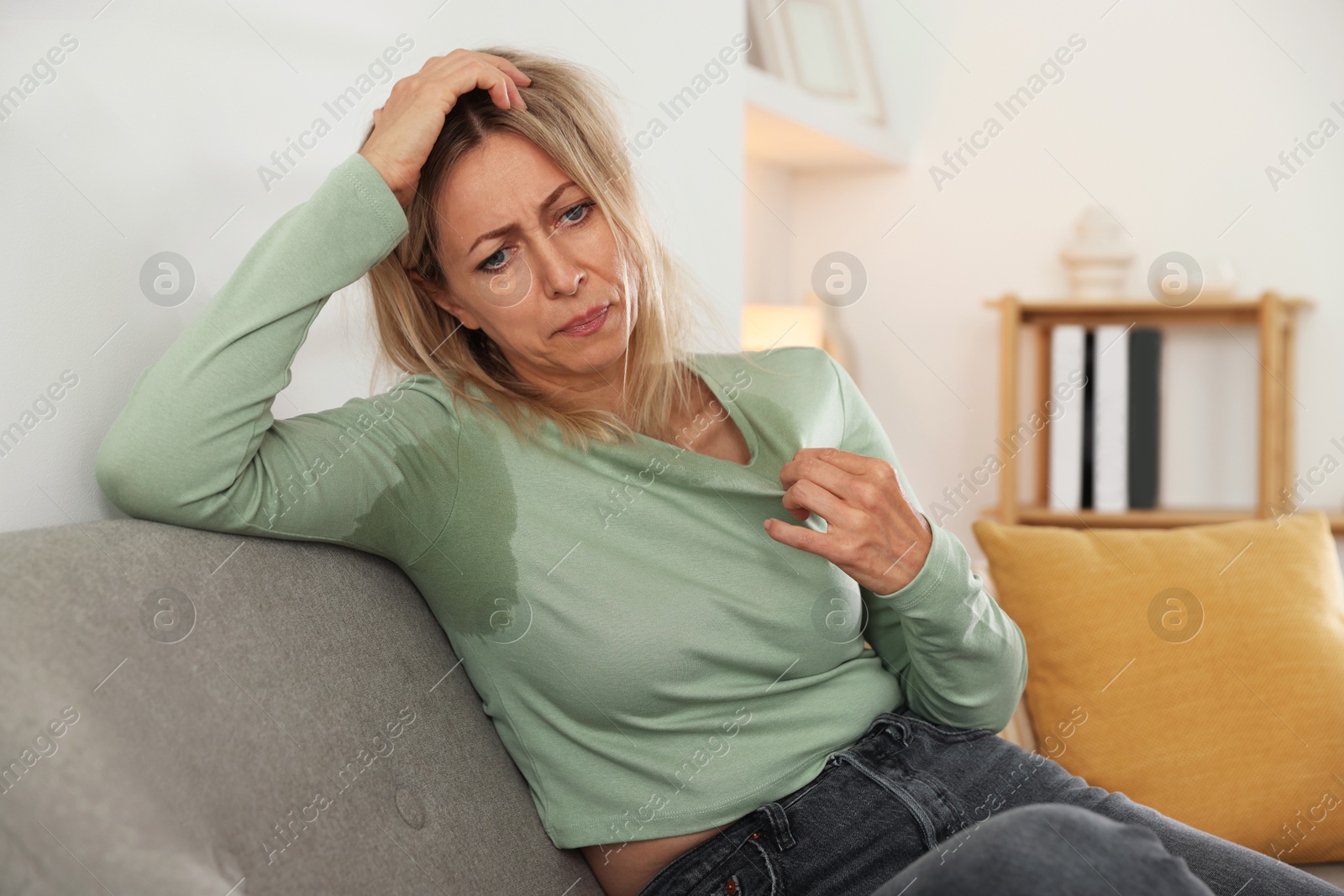 Photo of Menopause. Woman suffering from hot flash on sofa at home