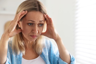 Photo of Menopause. Woman suffering from headache at home