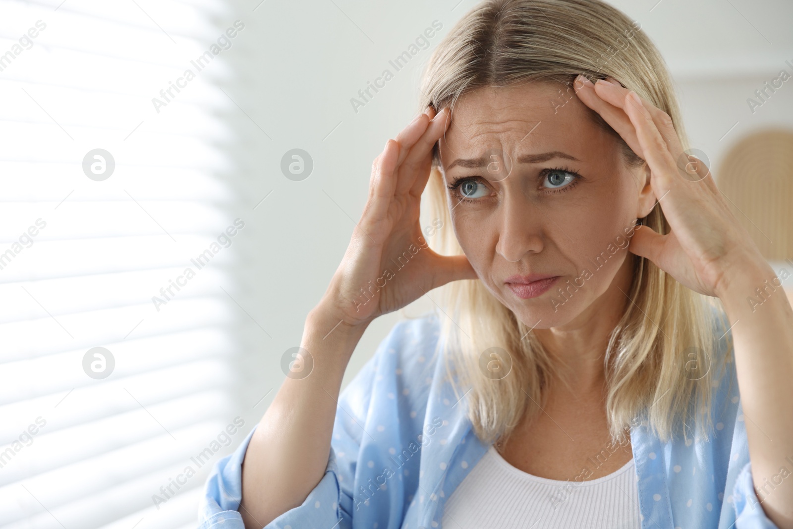 Photo of Menopause. Woman suffering from headache at home