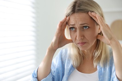 Menopause. Woman suffering from headache at home