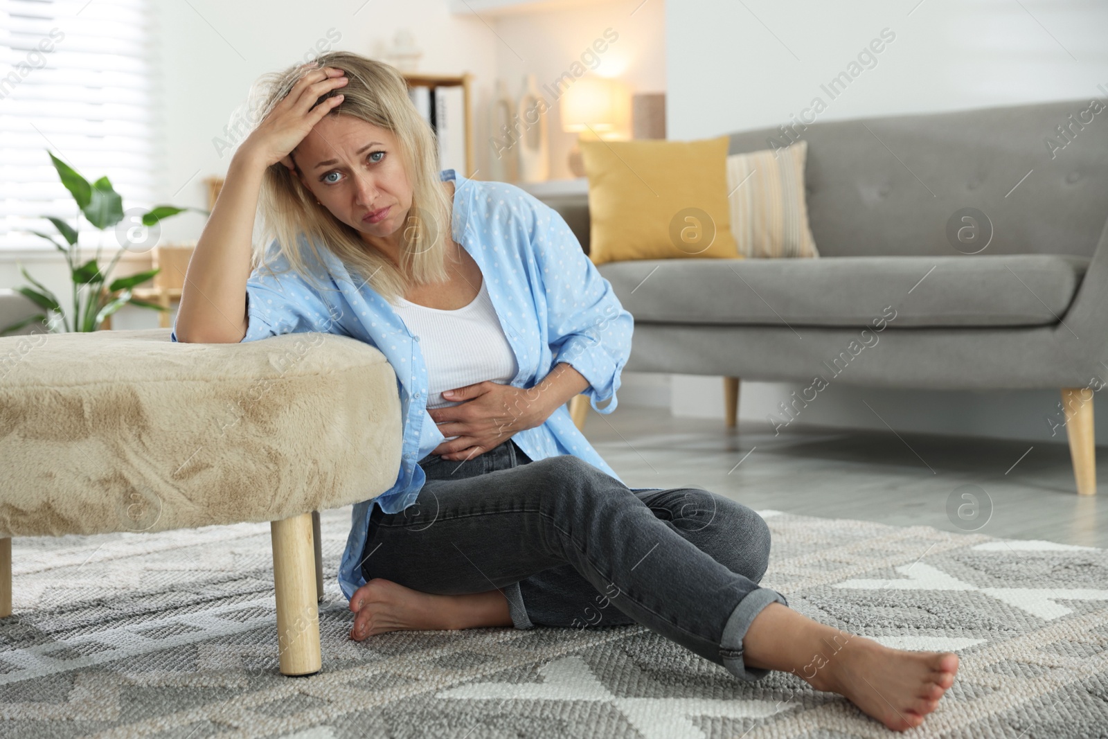 Photo of Menopause. Woman suffering from abdominal pain on floor at home