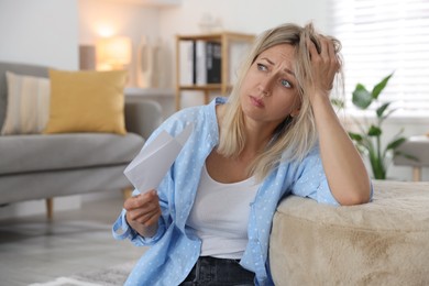 Photo of Menopause. Woman waving paper sheet to cool herself during hot flash at home