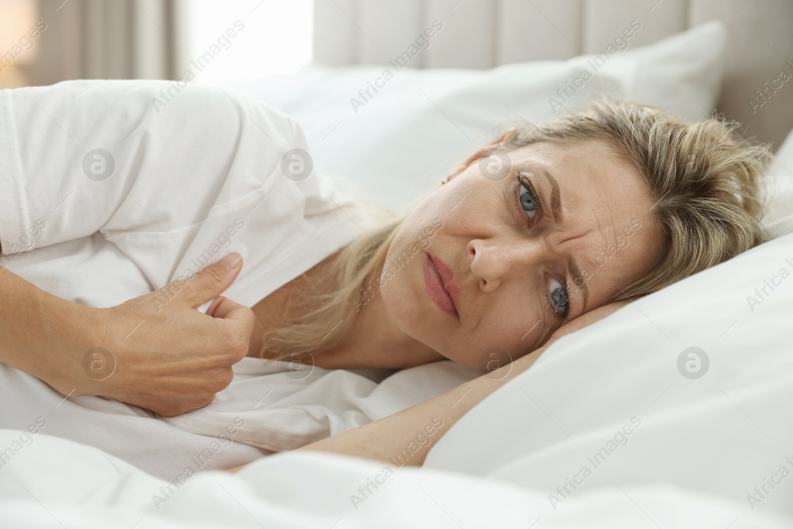 Photo of Menopause. Woman suffering from hot flash in bed at home