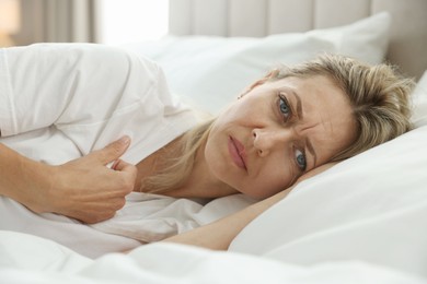 Menopause. Woman suffering from hot flash in bed at home