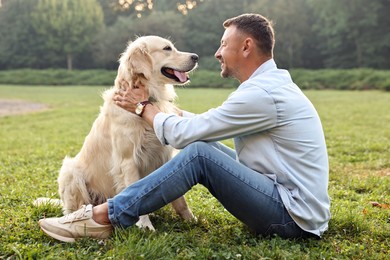 Photo of Smiling man with cute Golden Retriever dog on spring day