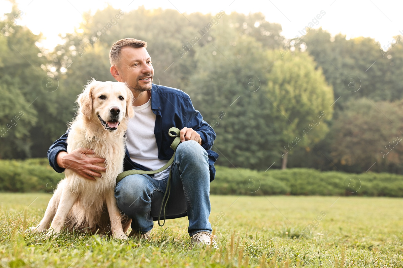 Photo of Smiling man with cute Golden Retriever dog on spring day, space for text