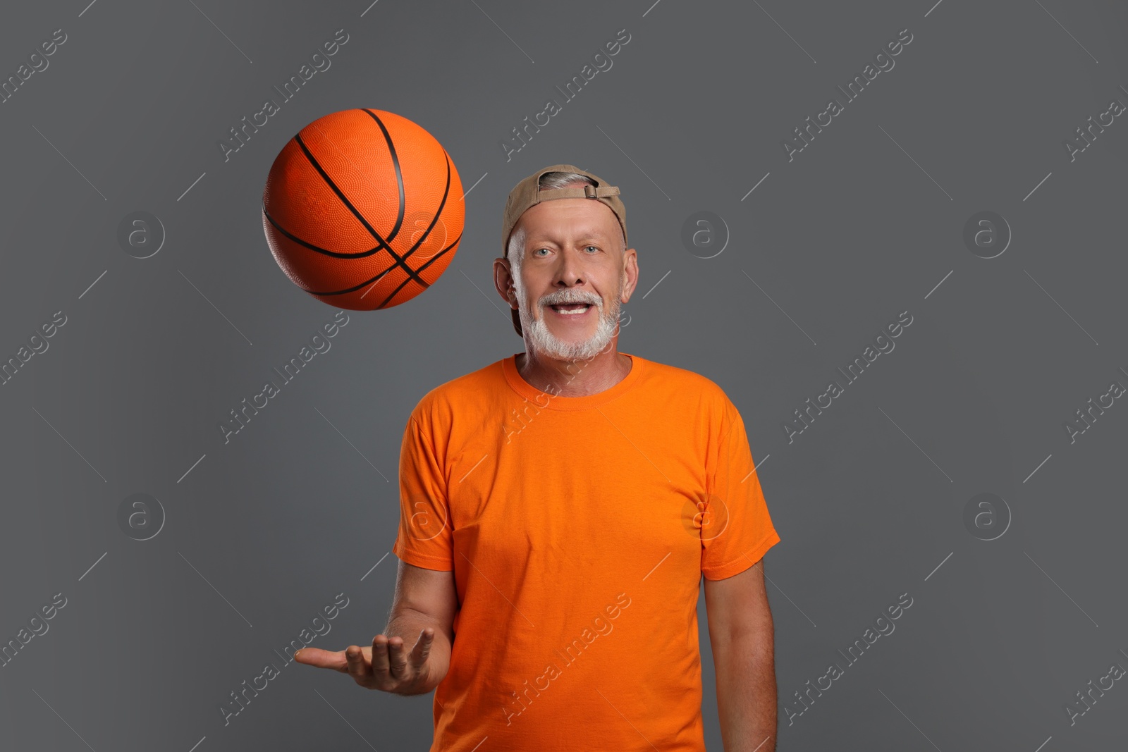 Photo of Portrait of handsome senior man with basketball ball on grey background