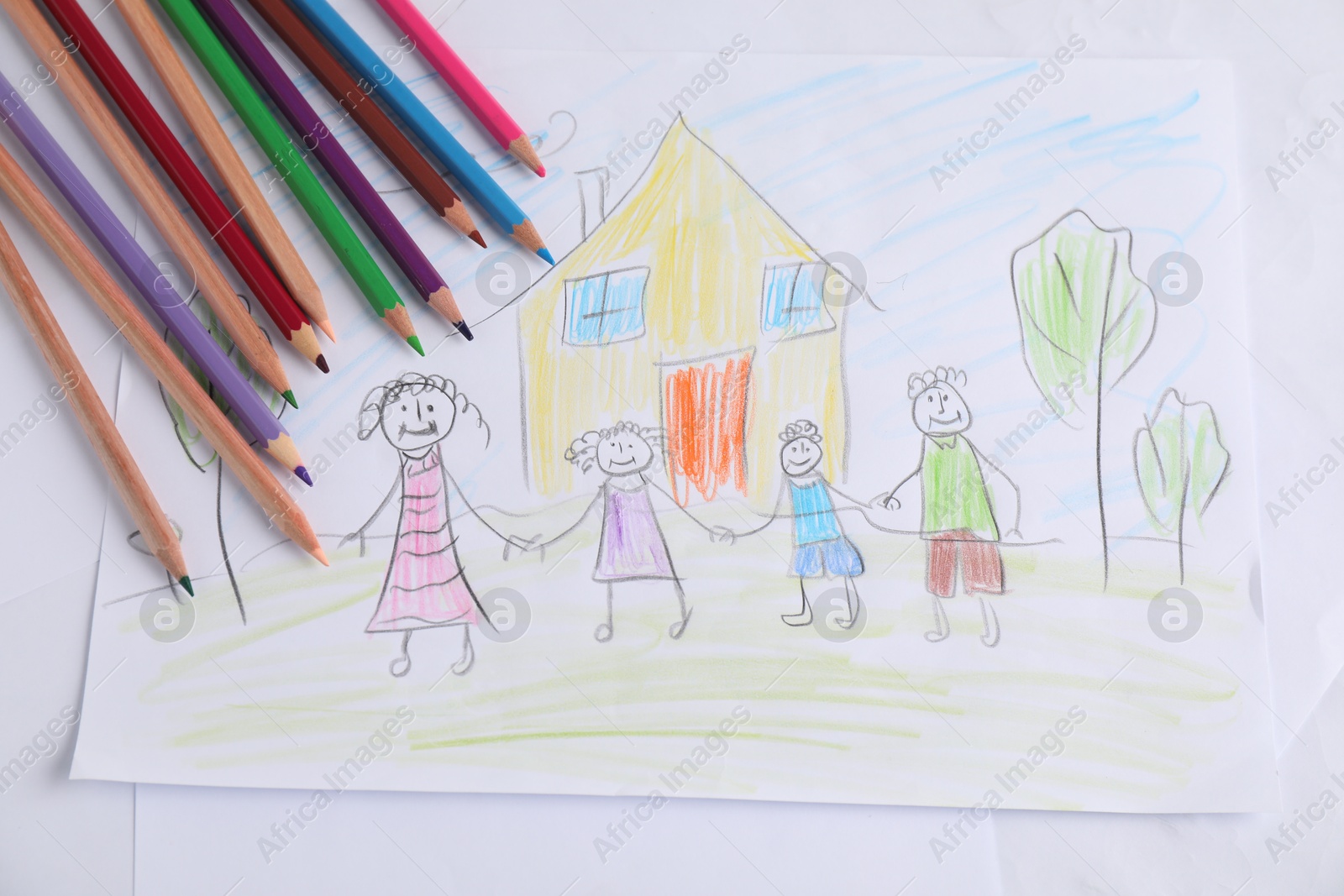 Photo of Child's drawing of happy family and pencils on table, top view