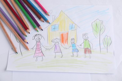 Photo of Child's drawing of happy family and pencils on table, top view