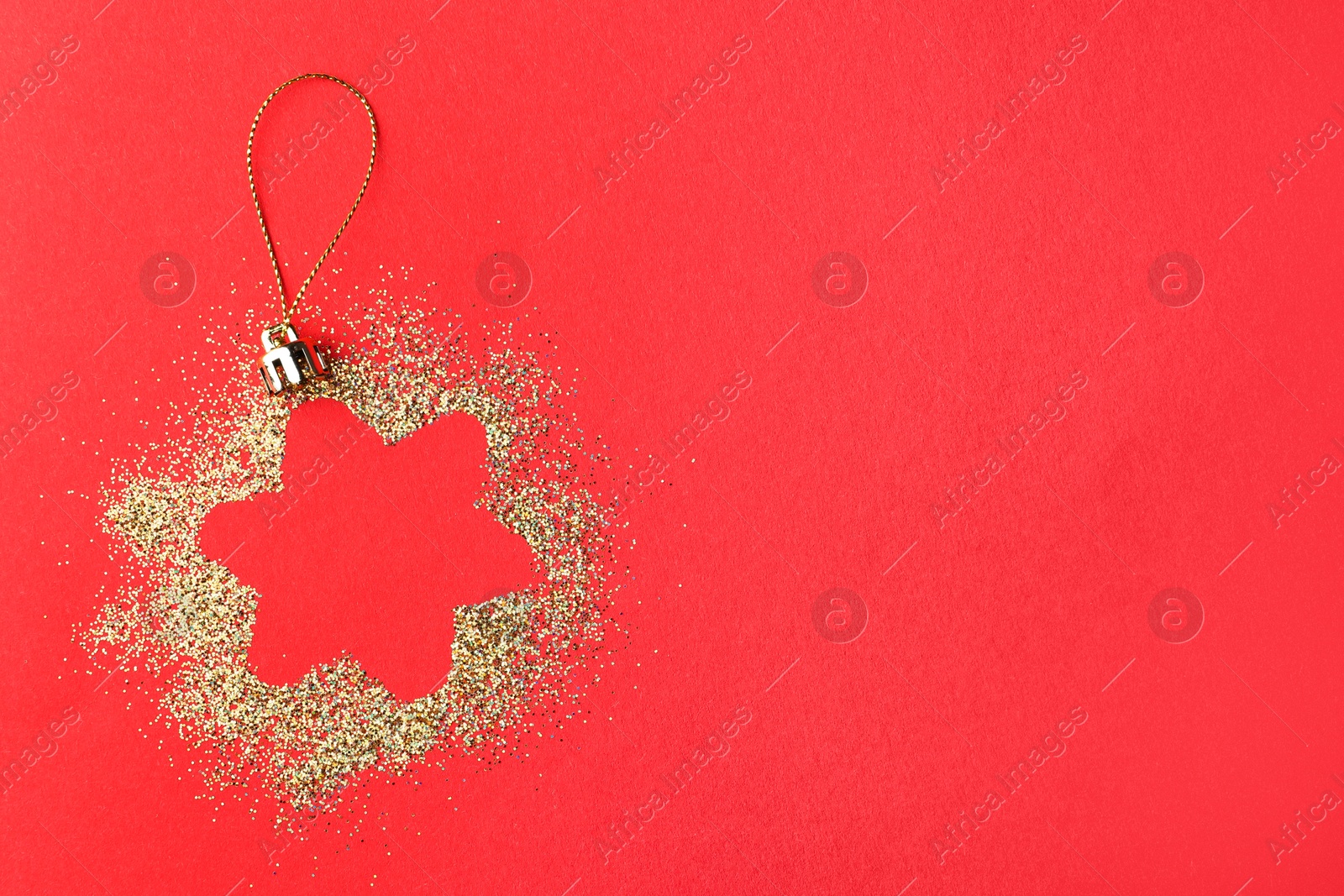 Photo of Christmas ornament made of golden glitter on red background, top view. Space for text