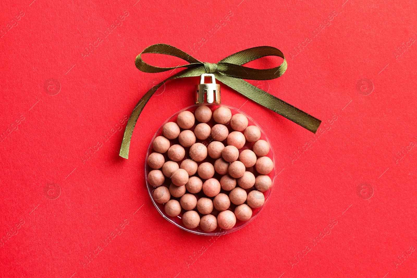 Photo of Christmas ball made with blush on red background, top view