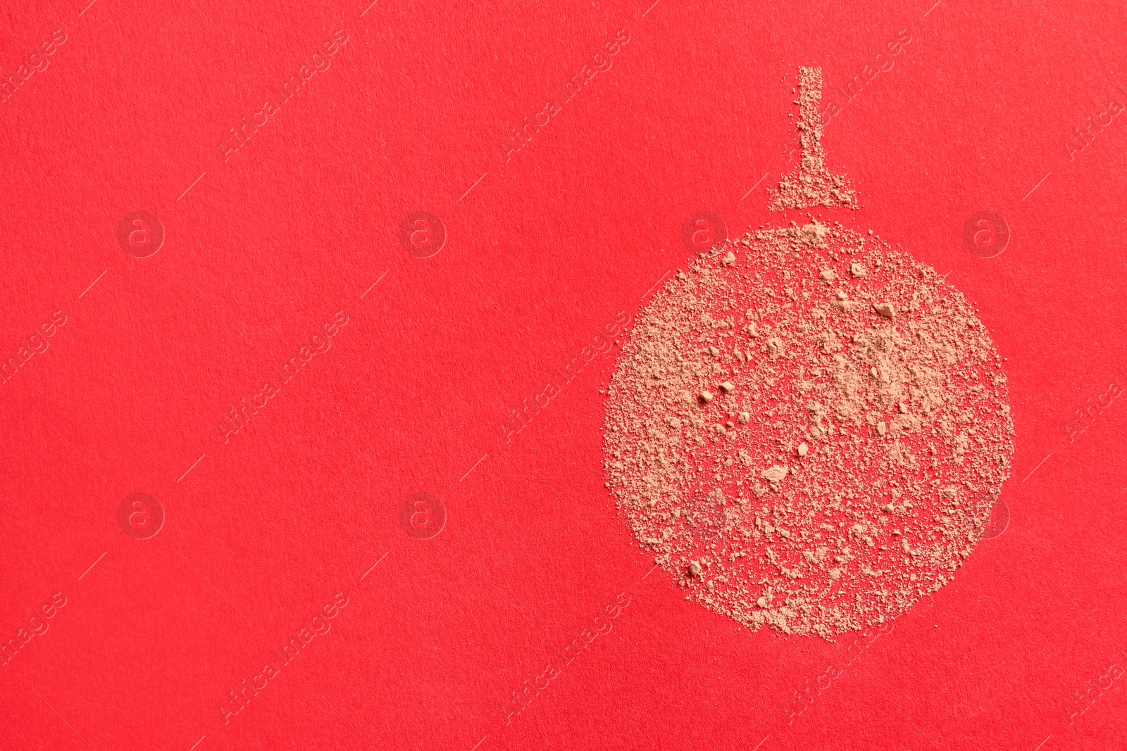 Photo of Christmas ball made with face powder on red background, top view. Space for text