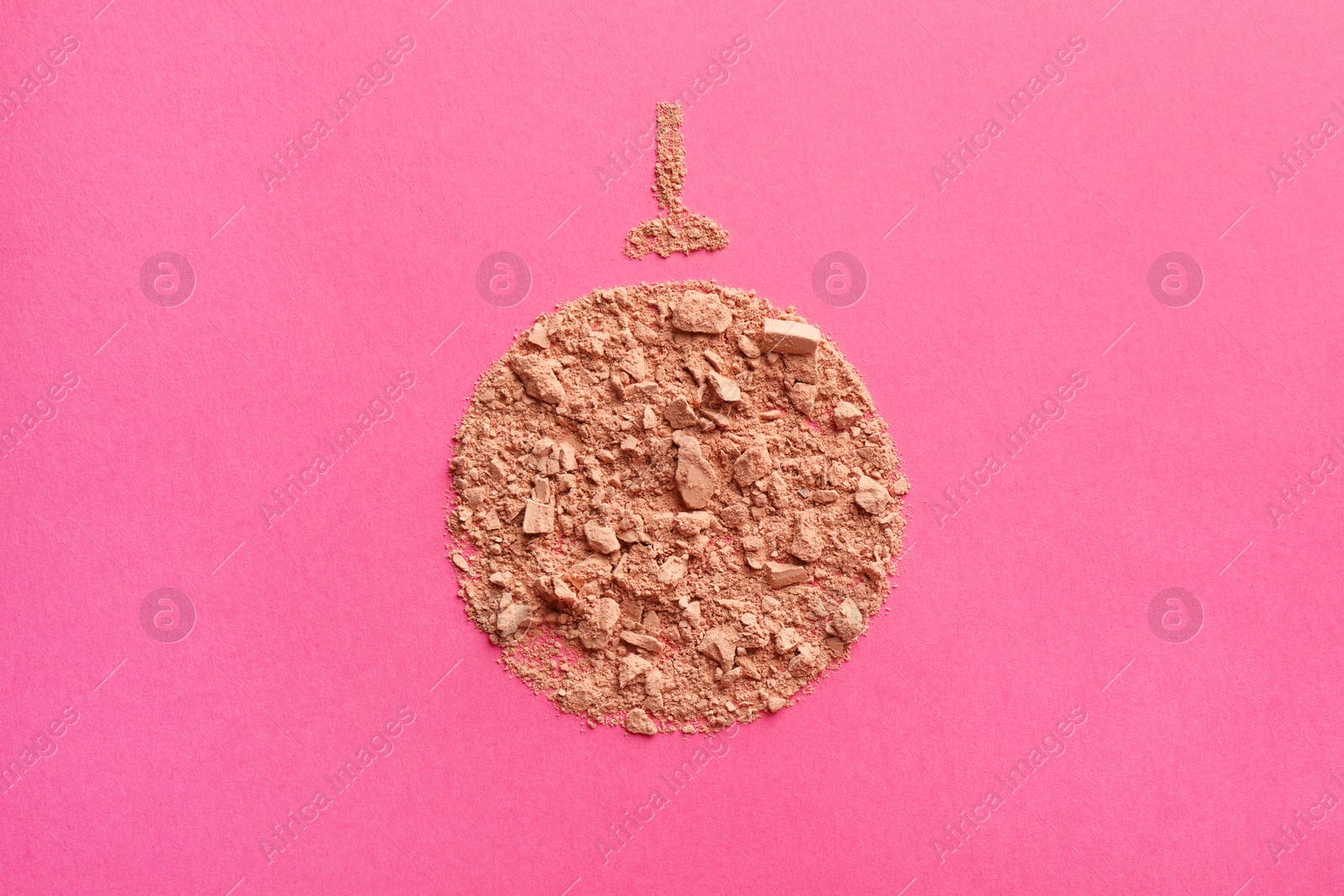 Photo of Christmas ball made with face powder on pink background, top view